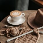 Coffee Drink Beside A Knitted Material On Wooden Table